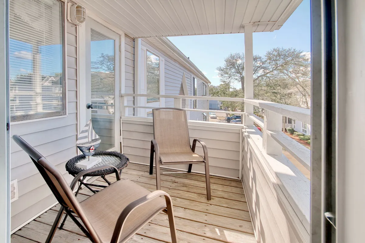 This image showcases an inviting balcony setup with chairs and a table, bordered by railings and overlooking a serene view. The arrangement suggests a perfect spot to start your day with coffee, enjoy a book, or simply relax while soaking in the surroundings.