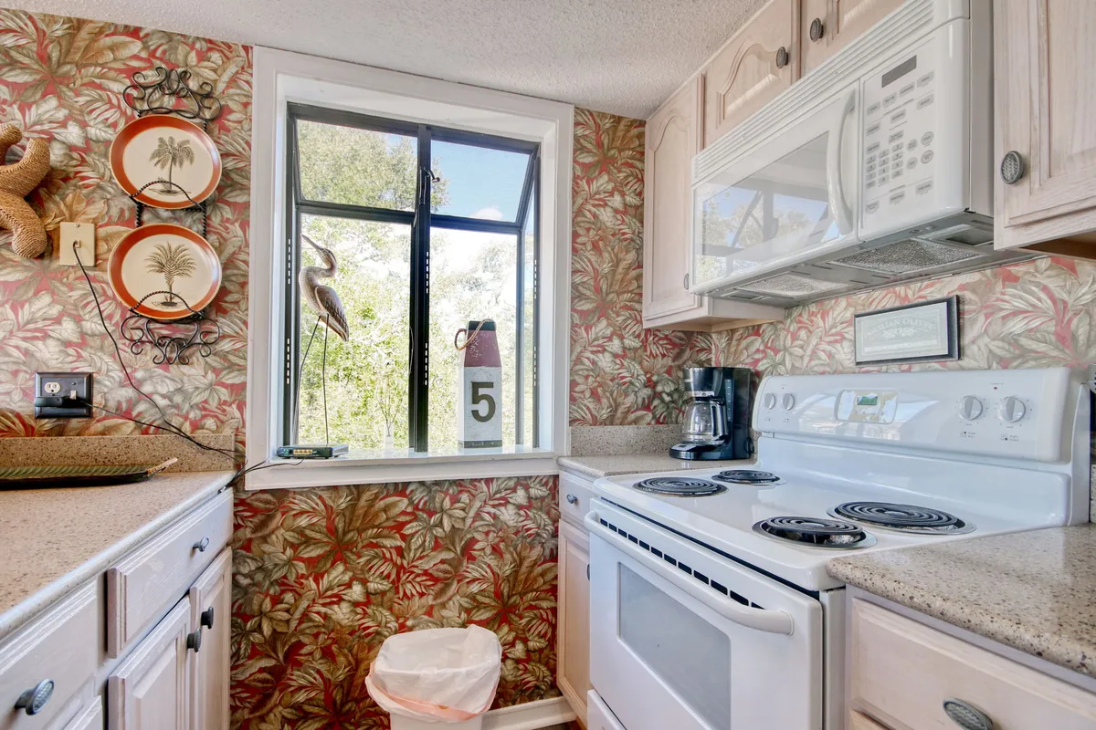 A different angle on the kitchen, showing a window with a view, decorative plates, stove, microwave, and coffee maker. The layout underscores the kitchen’s functionality and its ability to accommodate everything from elaborate dinners to quick coffee breaks.