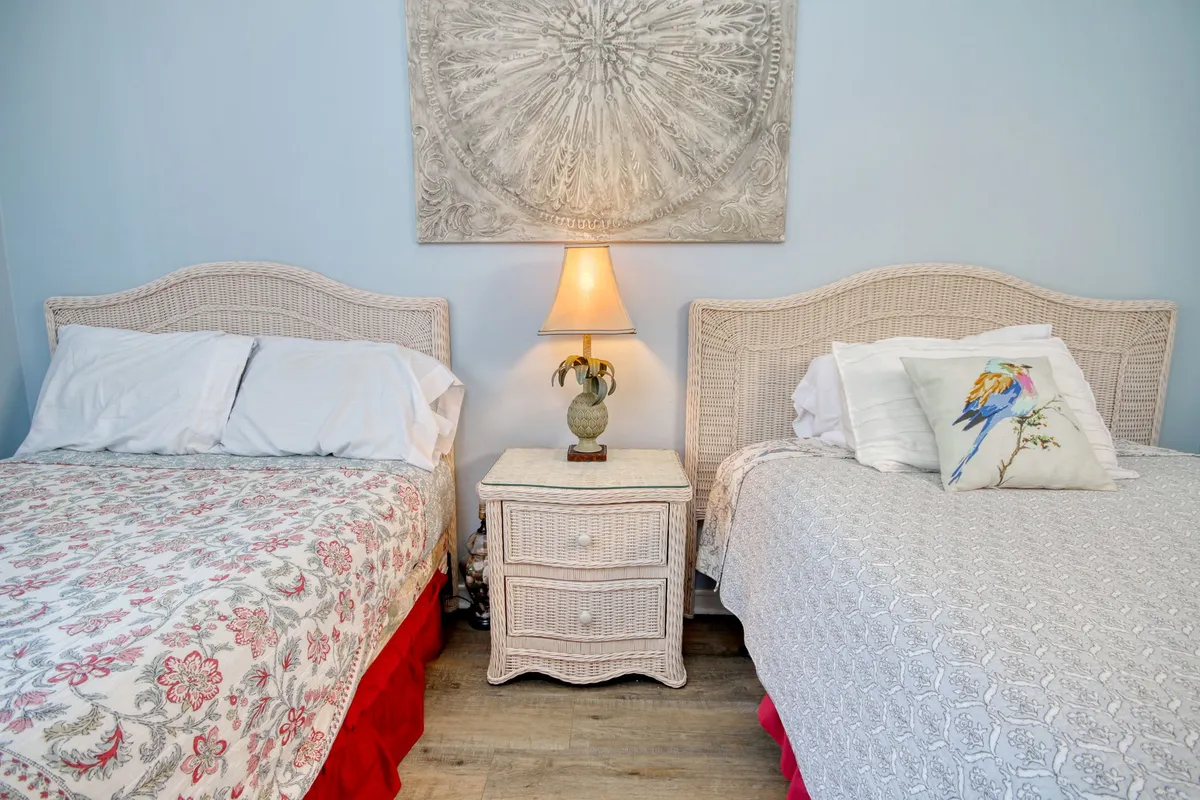 This room displays two neatly made beds, a central nightstand with a lamp, and tasteful wall art. The space is cozy and relaxed, perfect for families or friends seeking privacy and a comfortable place to unwind after a busy day.